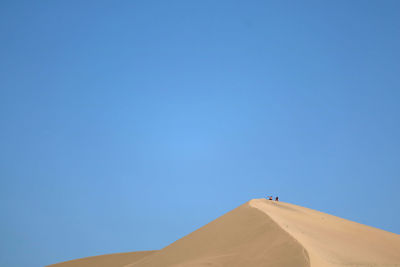 Low angle view of desert against clear blue sky