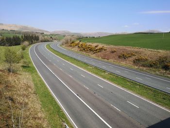 Scenic view of road amidst field against sky