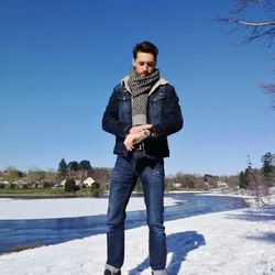 Young man using mobile phone against clear blue sky