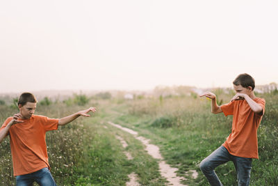 Funny twin brother boys playing outdoors on field at sunset.