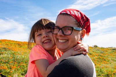 Portrait of happy father with daughter against sky on field