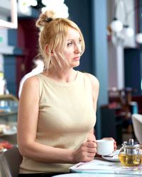 Thoughtful woman with coffee cup on table sitting in cafe