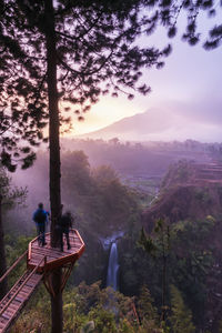 Rear view of people standing on mountain against sky