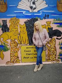 Full length of woman standing against graffiti wall