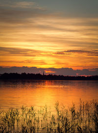 Scenic view of lake against dramatic sky during sunset