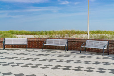 Chairs on table by sea against sky