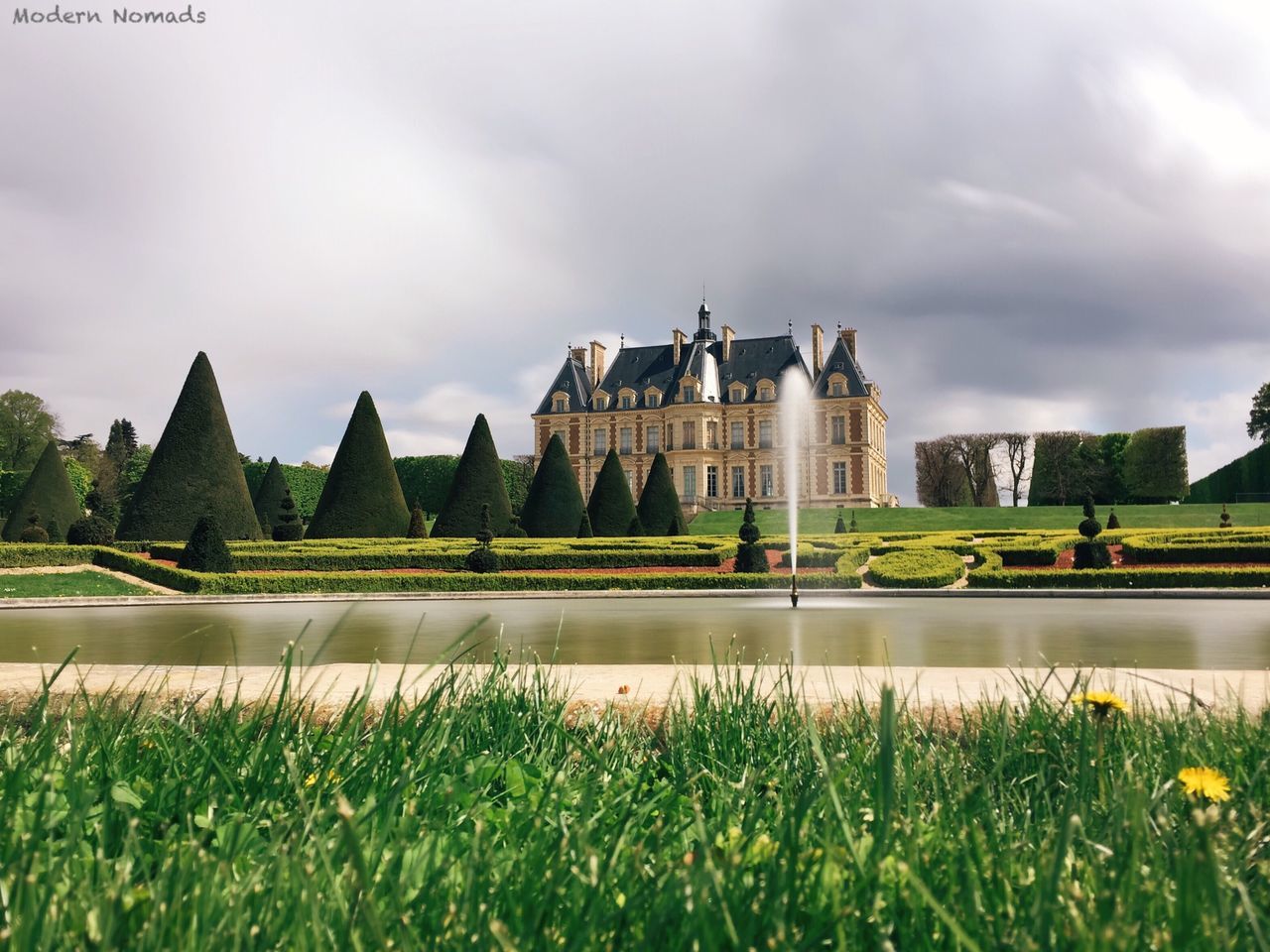 architecture, built structure, building exterior, sky, cloud - sky, cloudy, grass, famous place, plant, cloud, travel destinations, green color, water, tree, history, city, travel, growth, day, tourism