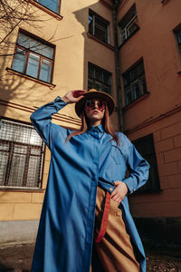 Portrait of smiling young woman standing against building