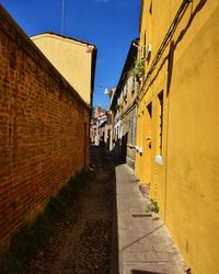 Walkway amidst buildings against sky