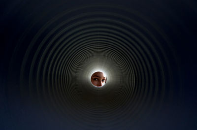 Portrait of woman peeking through pipe