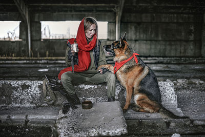 Full length of woman with dog sitting outdoors