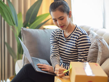 Young man using laptop while sitting on sofa at home