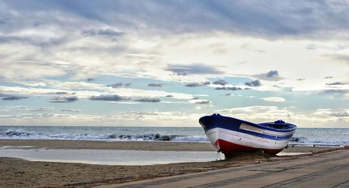 Boat moored on beach against sky