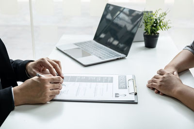 Cropped image of candidate and manager sitting at office