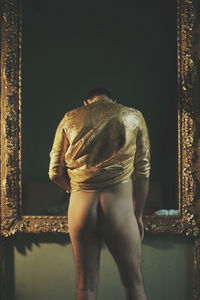 Rear view of shirtless man looking at sculpture