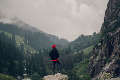 Rear view of man walking on mountain against sky