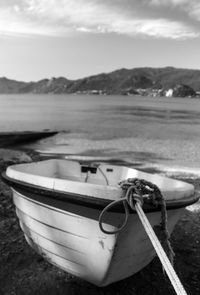 Boat moored on beach against sky