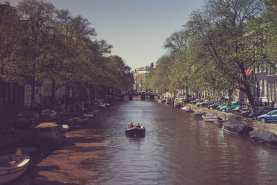 People on boats in water against sky