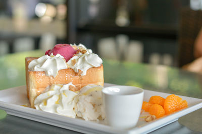 Honey toast with red homemade ice cream and whipping cream topping serve with orange.