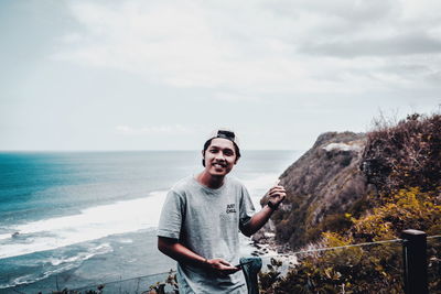 Portrait of young man standing in sea against sky