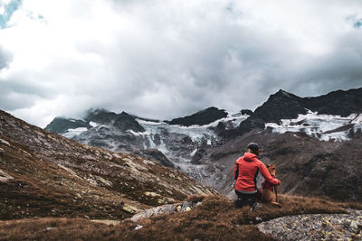 Rear view of man standing on mountain against sky