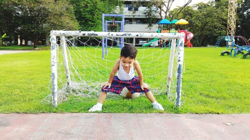 Full length of cute boy standing against goal post on soccer field