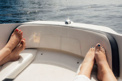 Friends laying out in sun on bow of motor boat, tanning feet on lake