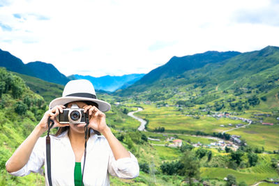 Man photographing on mountain against sky