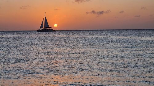 Sailboat sailing on sea against sky during sunset