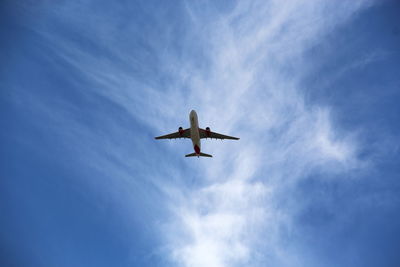 Low angle view of airplane flying against blue sky