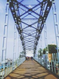 People walking on footbridge against sky