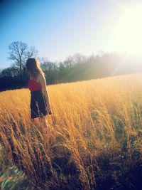 Rear view of woman standing in field during sunset