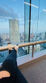 Low section of person on railing against buildings in city