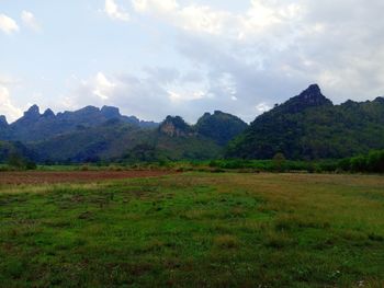 Scenic view of green landscape and mountains against sky