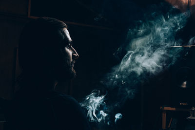 Man looking at smoke in darkroom