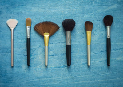 Close-up of various make-up brushes in row on wooden table