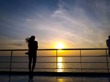 Silhouette woman standing on boat deck against sky during sunset