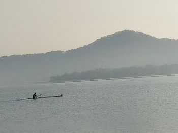 Scenic view of lake by silhouette mountain against sky