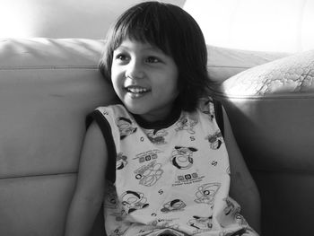 Smiling girl sitting on sofa at home