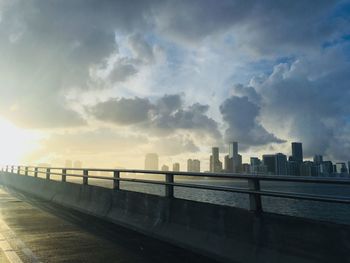 City by river against sky during sunset