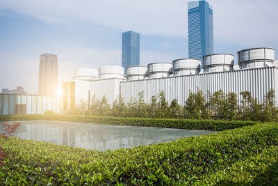 View of factory by lake against sky