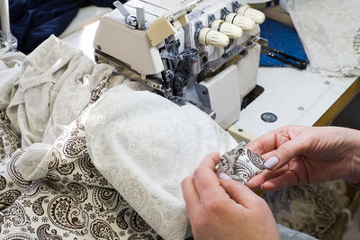 Cropped hands of woman using sewing machine