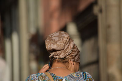 Rear view of woman head covered with scarf while using smart phone