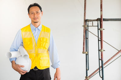Portrait of smiling man standing against yellow wall
