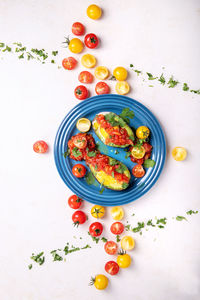 High angle view of egg in avocado with cherry tomatoes served in plate on table