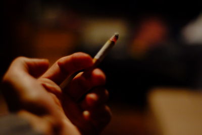 Cropped hand of person holding lit cigarette