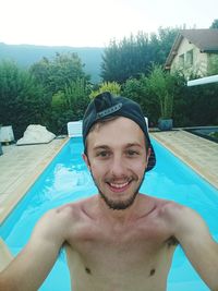 Portrait of smiling man in swimming pool against trees