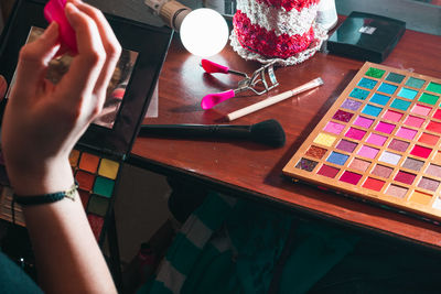 Woman in front of her dressing table holding her palette of colored shadows that is worn out.