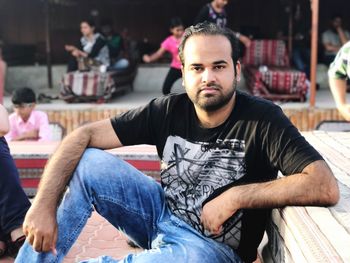 Portrait of confident young man sitting at outdoor restaurant