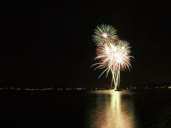 Firework display over river against sky at night